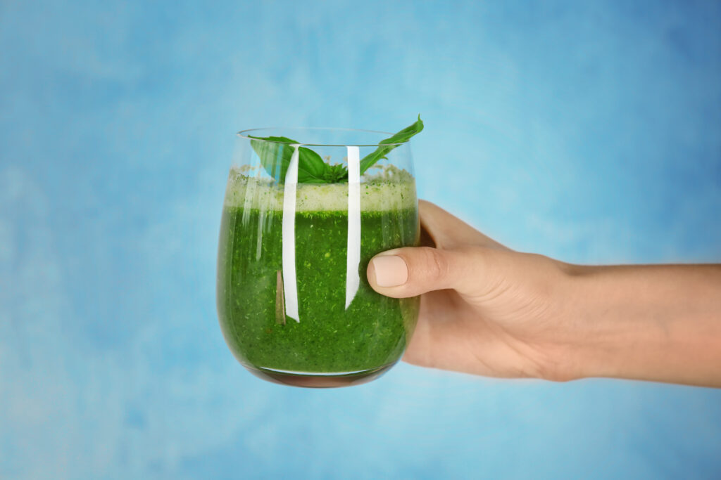The current image has no alternative text. The file name is: woman-s-hand-holding-glass-with-green-smoothie-light-background-1-scaled.jpg